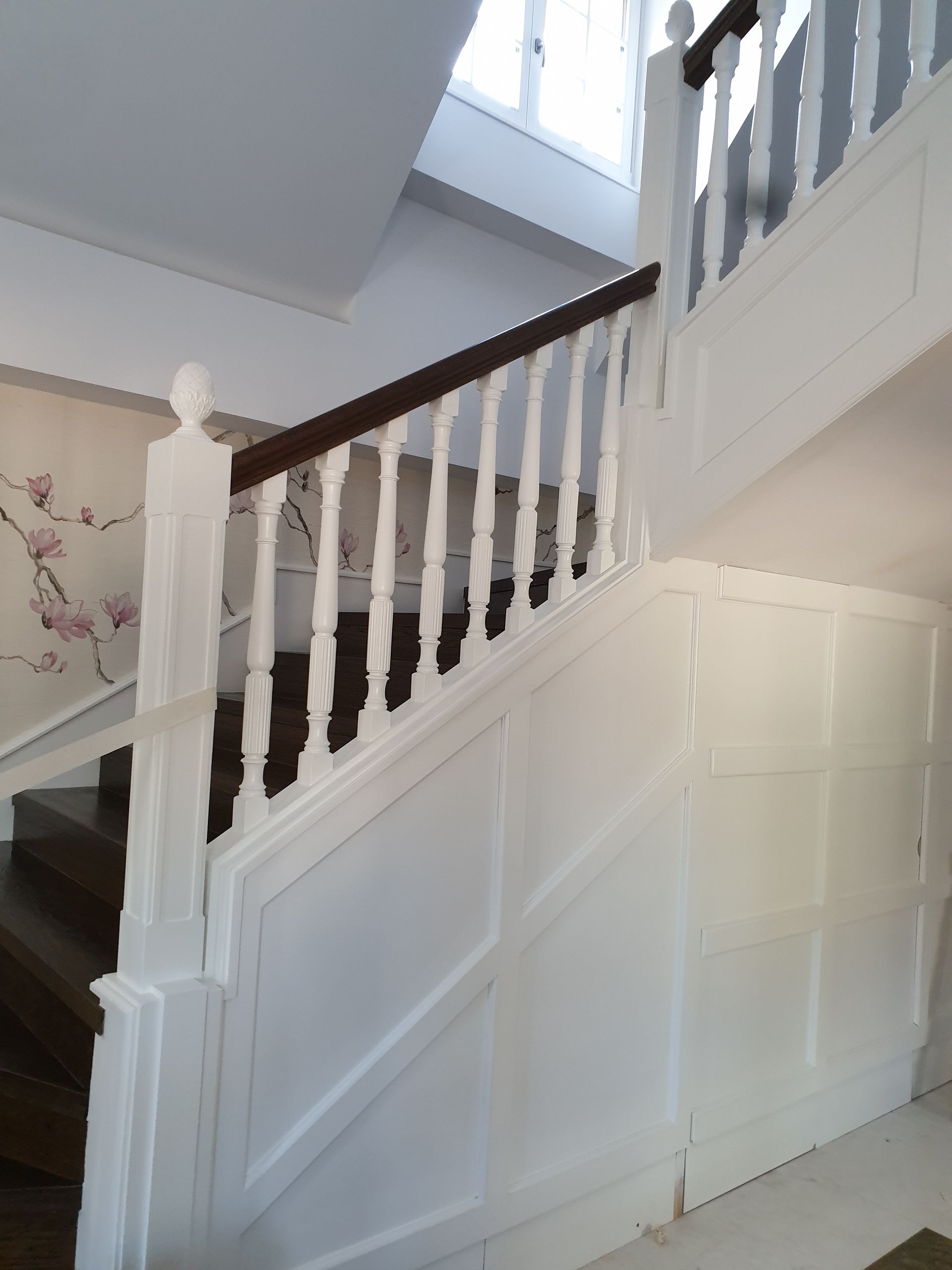 Una escalera blanca con barandilla de madera en una casa.