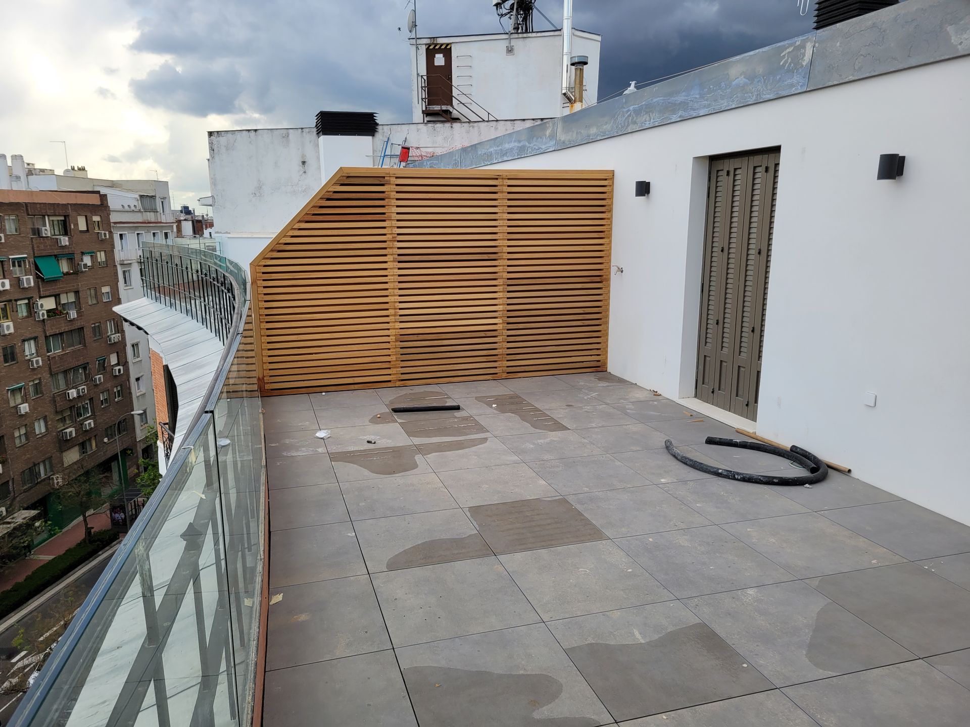 Un balcón con valla de madera y barandilla de cristal.