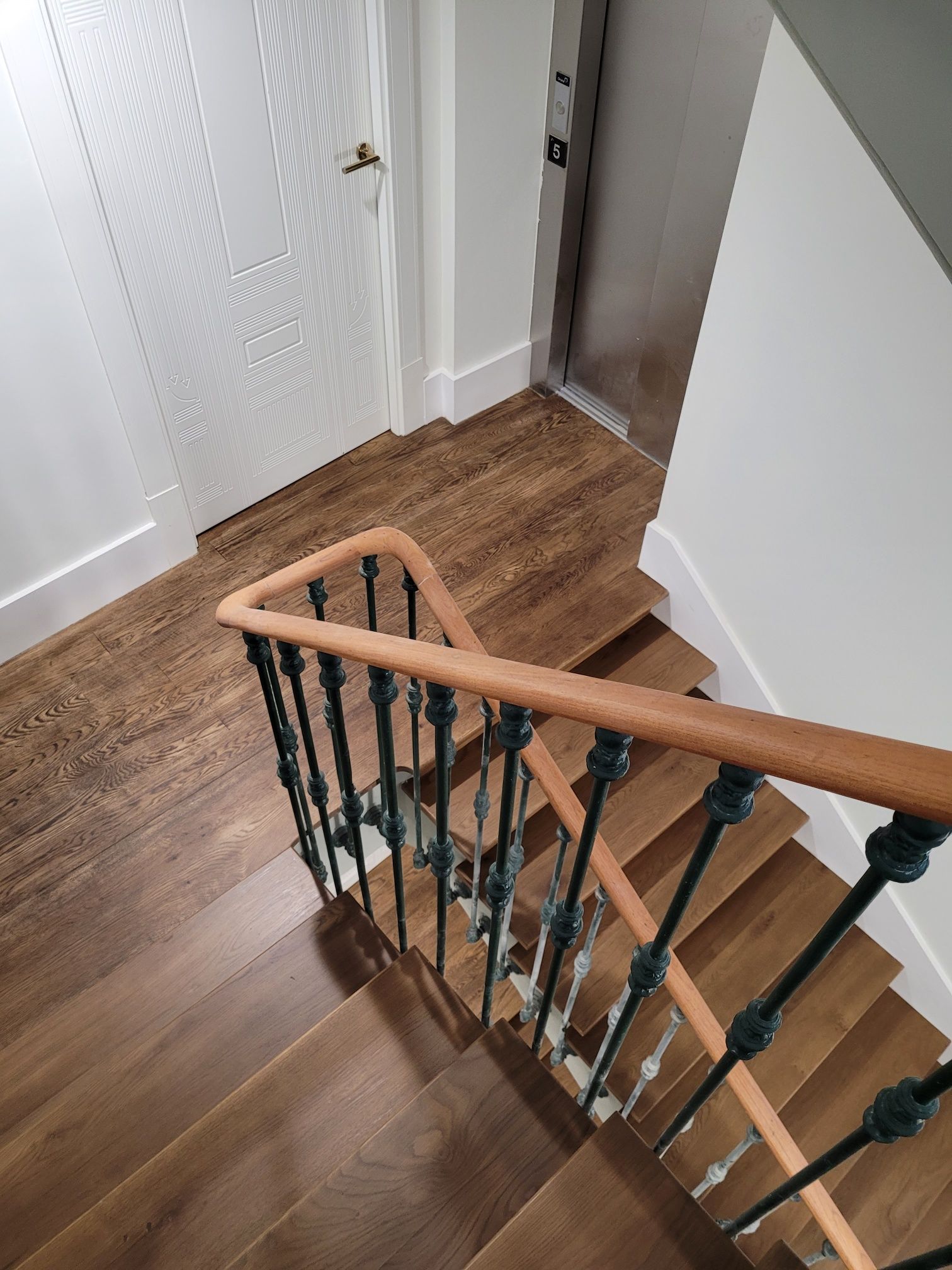 Una escalera de madera con barandilla de metal y pasamanos de madera