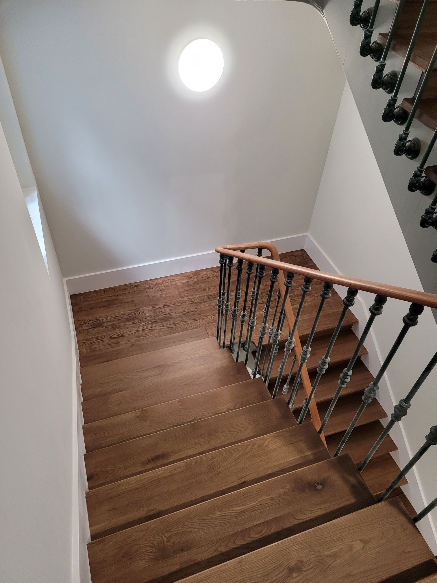 Una escalera de madera con barandilla de hierro forjado en una casa.
