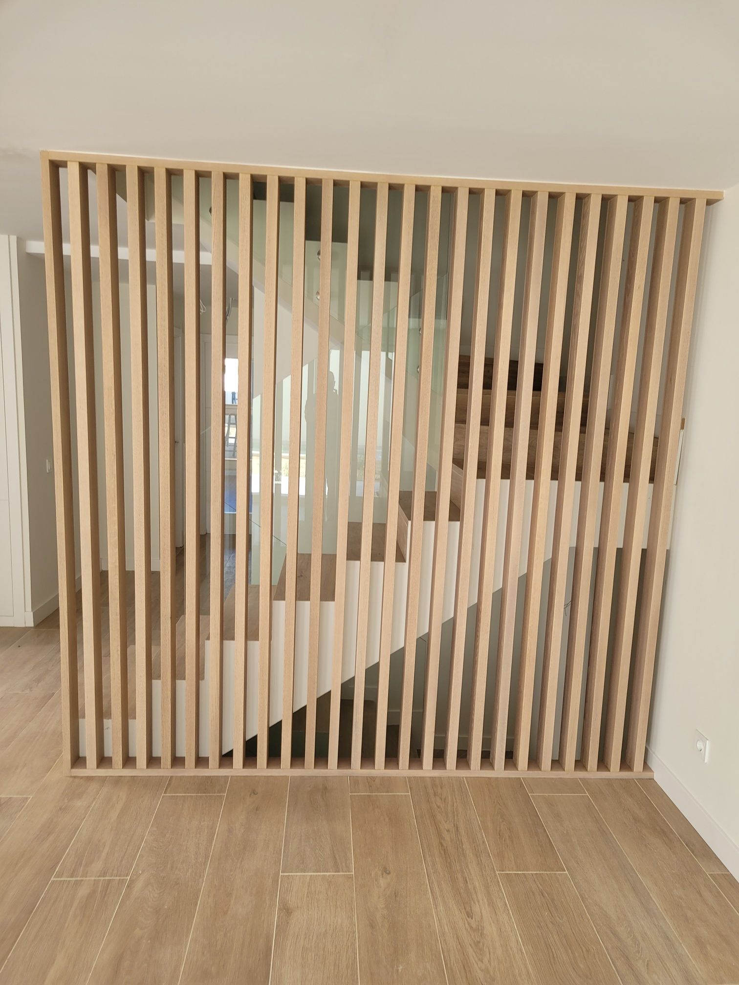 Una escalera de madera está detrás de un divisor de madera en una habitación.