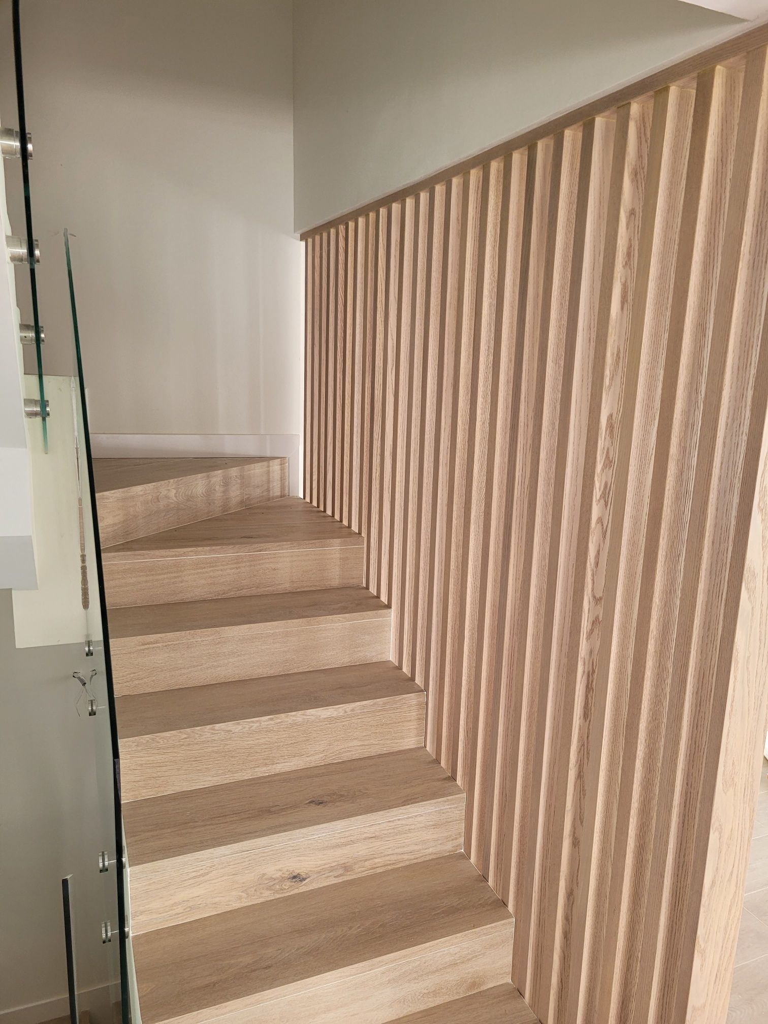 Una escalera con barandilla de madera y barandilla de cristal.