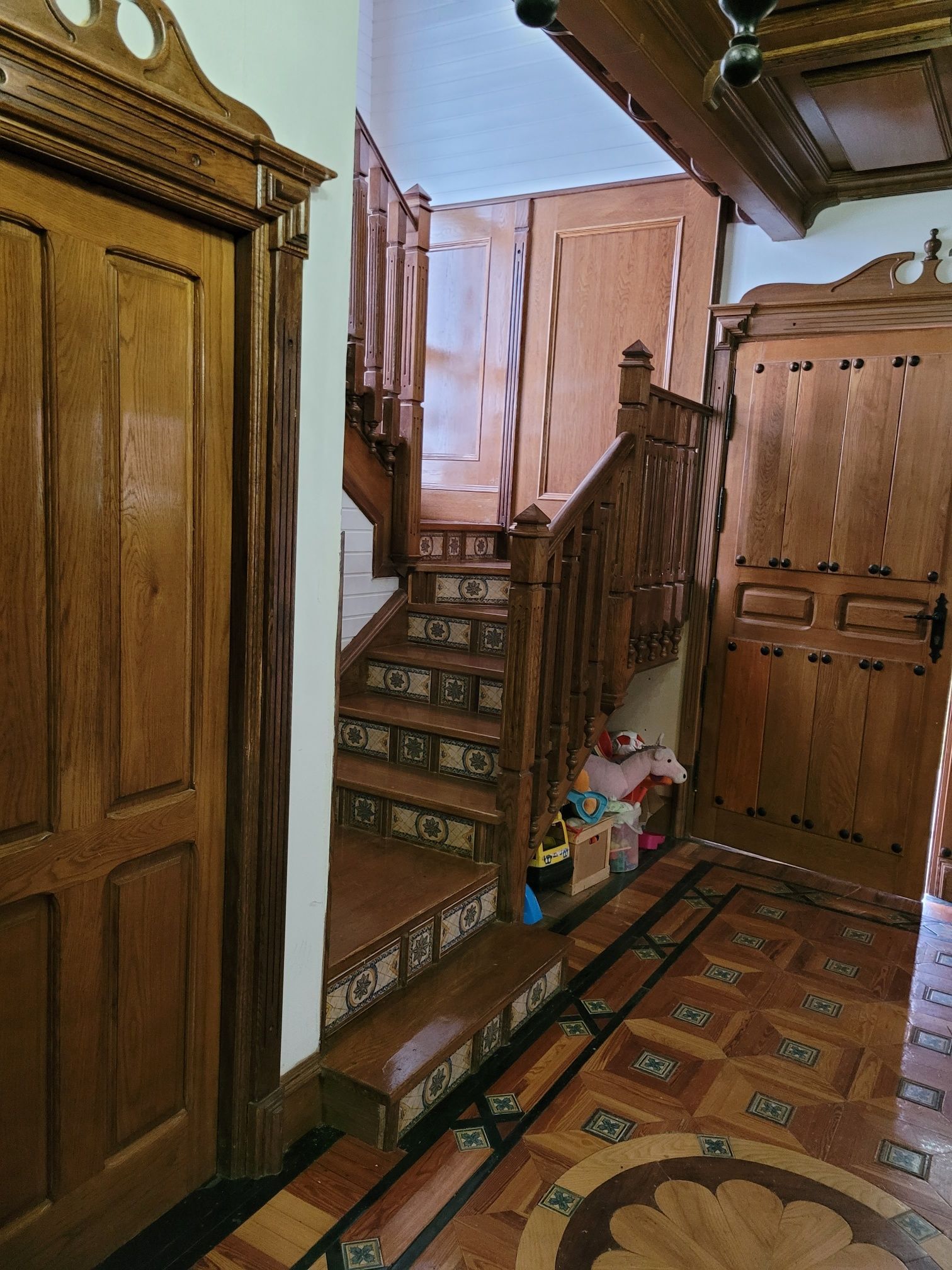 Un pasillo con una escalera de madera y una puerta de madera.