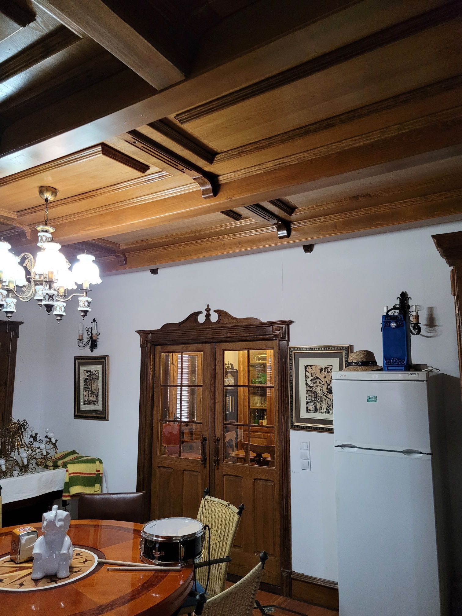 Un comedor con una mesa, sillas, un tambor y un refrigerador.