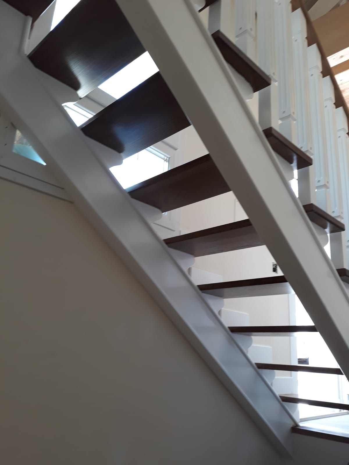 Una escalera con barandilla blanca y escalones de madera.