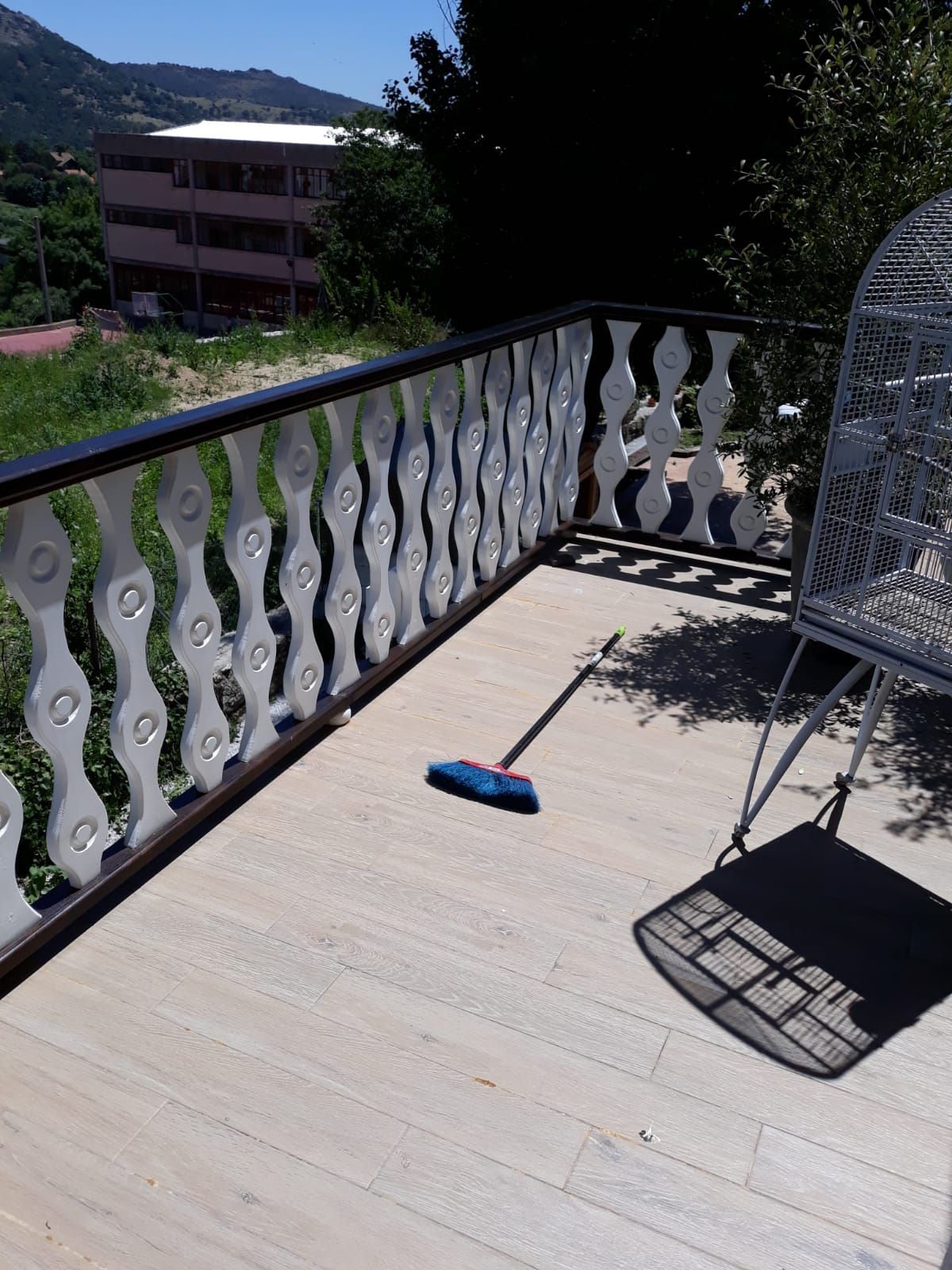 Un balcón con una silla y una escoba encima.