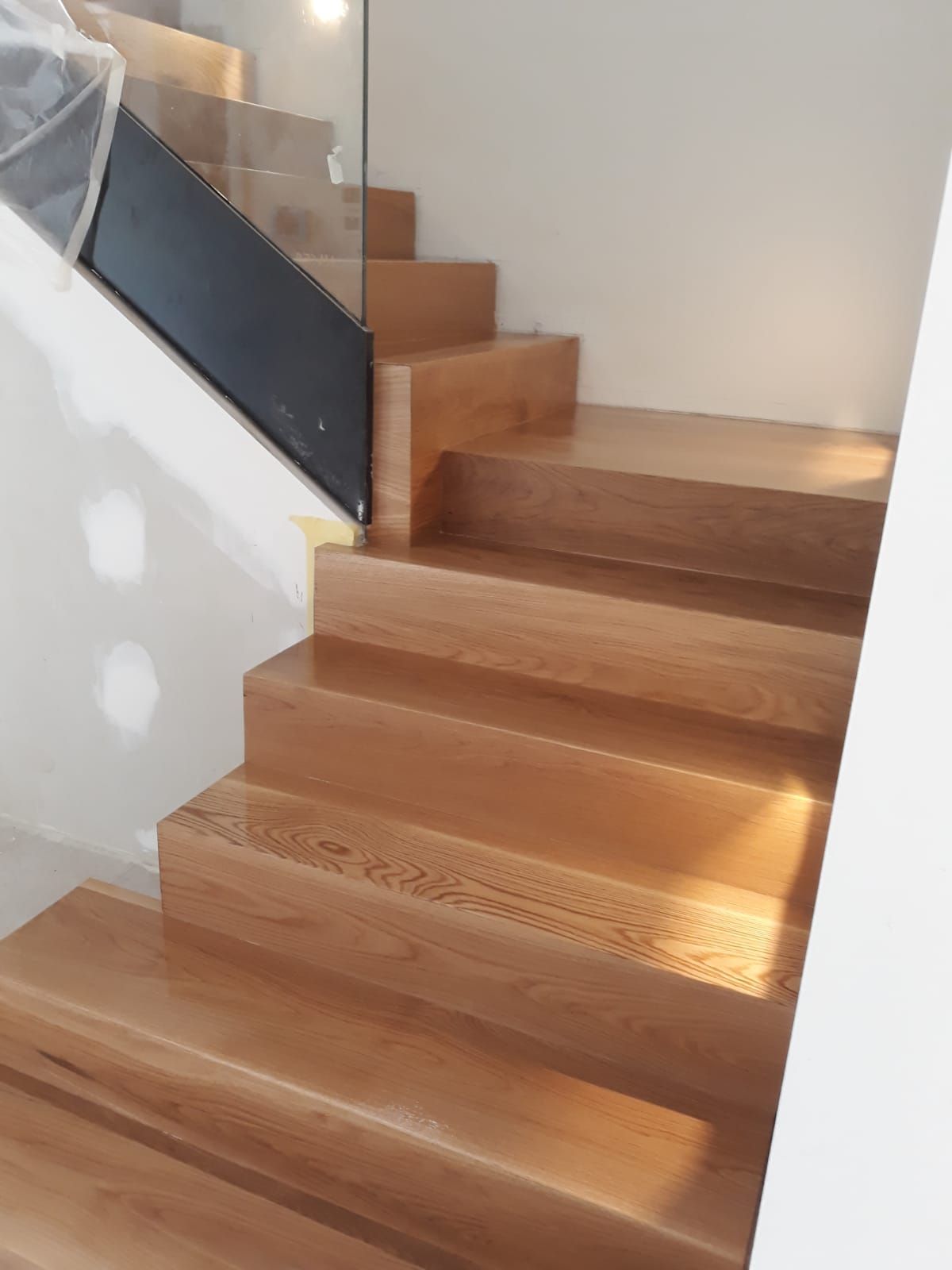 Una escalera de madera con barandilla de cristal en una casa.