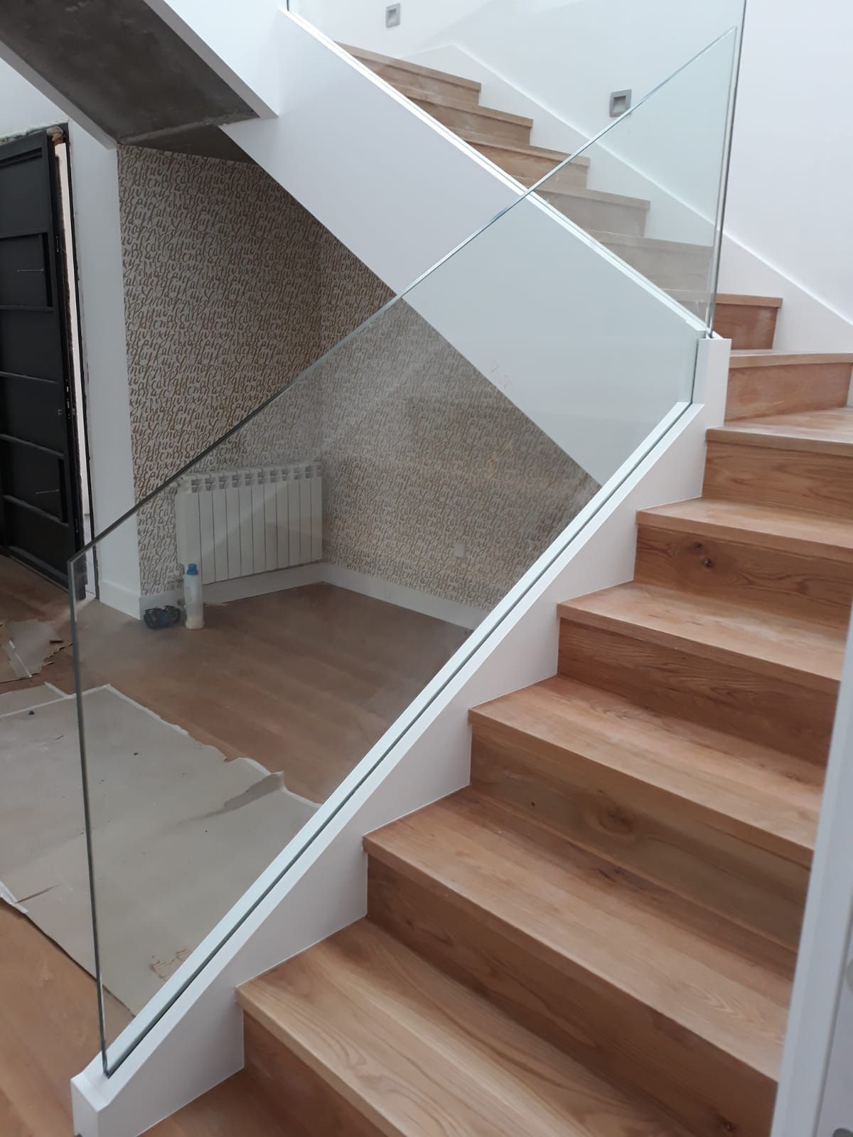 Una escalera con escalones de madera y barandilla de cristal.