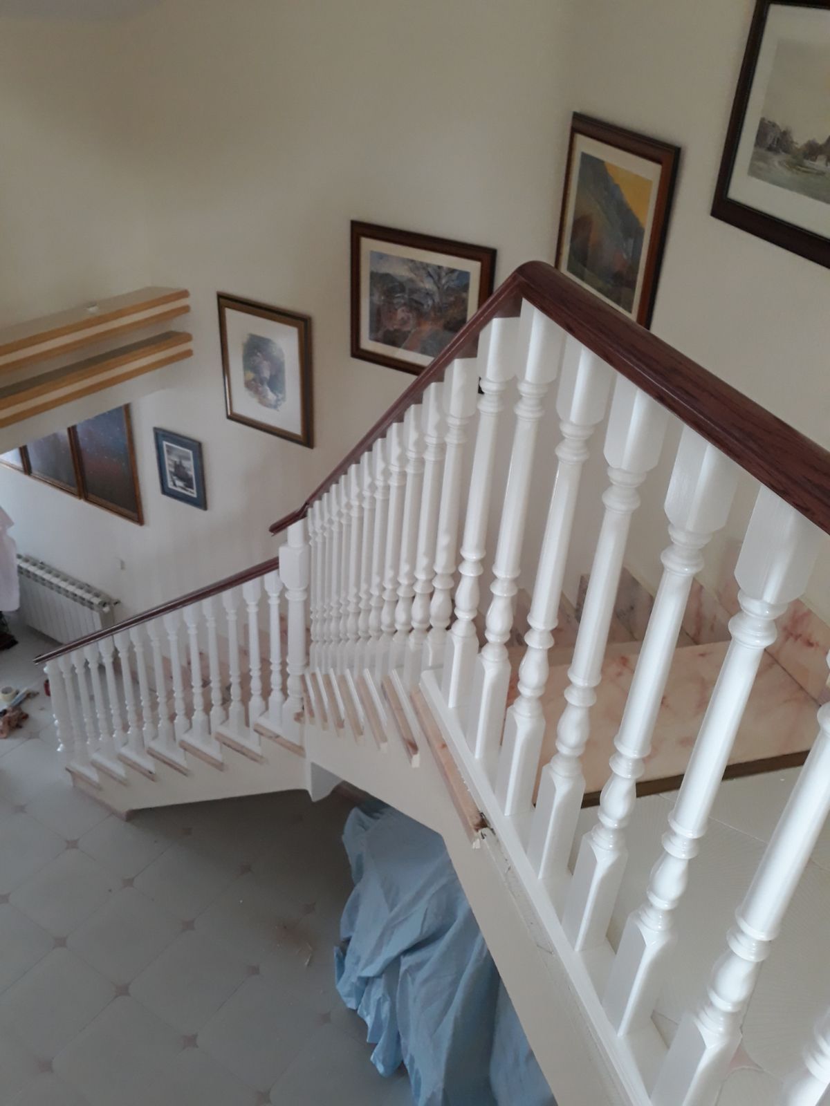 Una escalera con barandilla blanca y cuadros en la pared.
