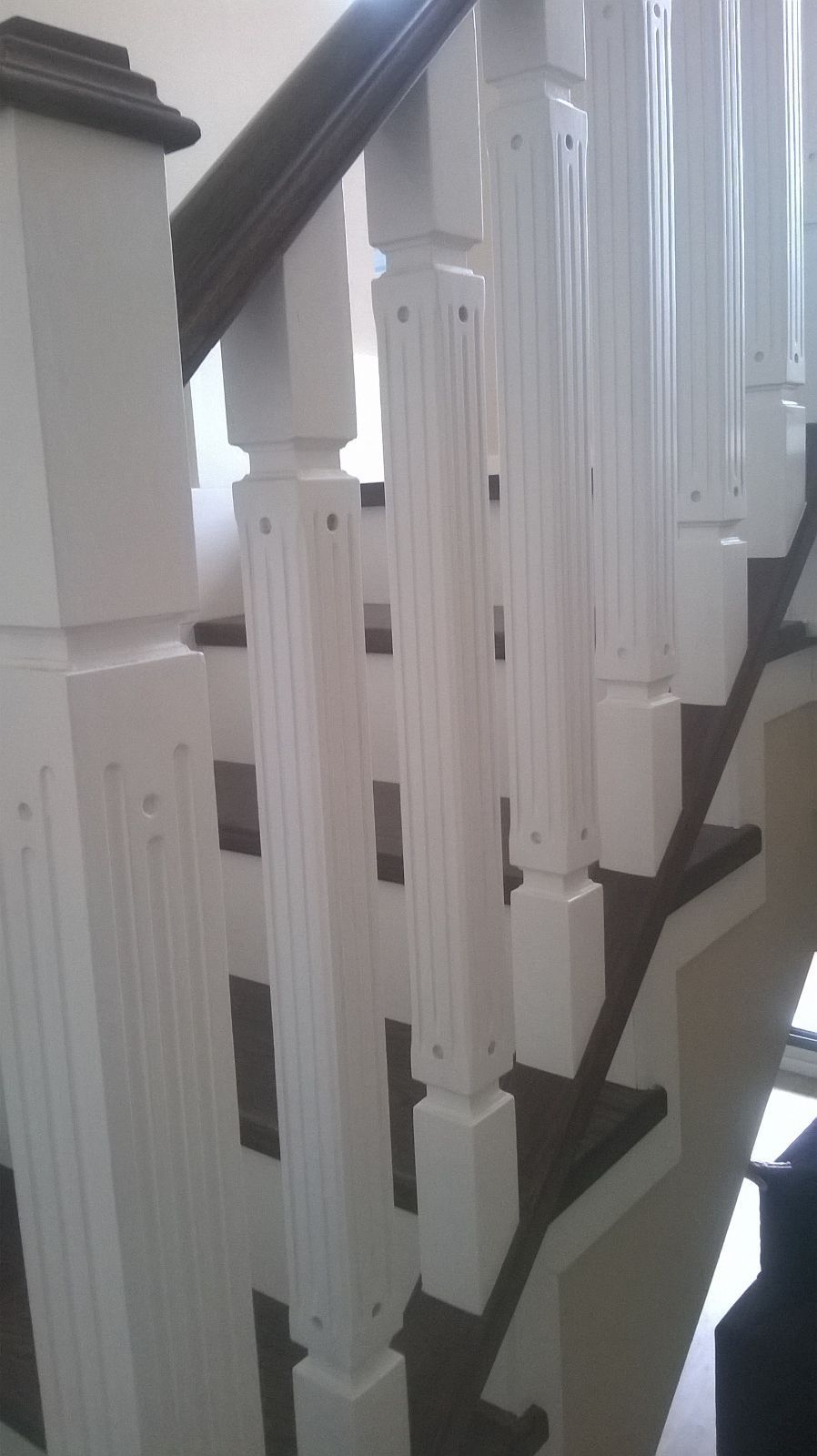 Un primer plano de una escalera con barandillas blancas y escalones negros.