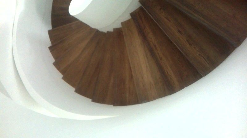 Un primer plano de una escalera de caracol de madera con una barandilla blanca.