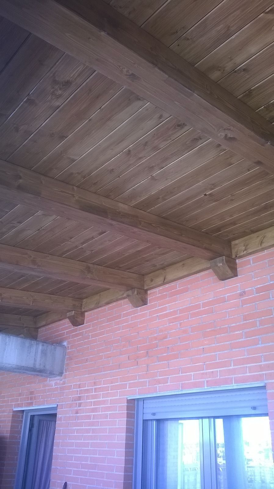 Un techo de madera con una pared de ladrillo al fondo.