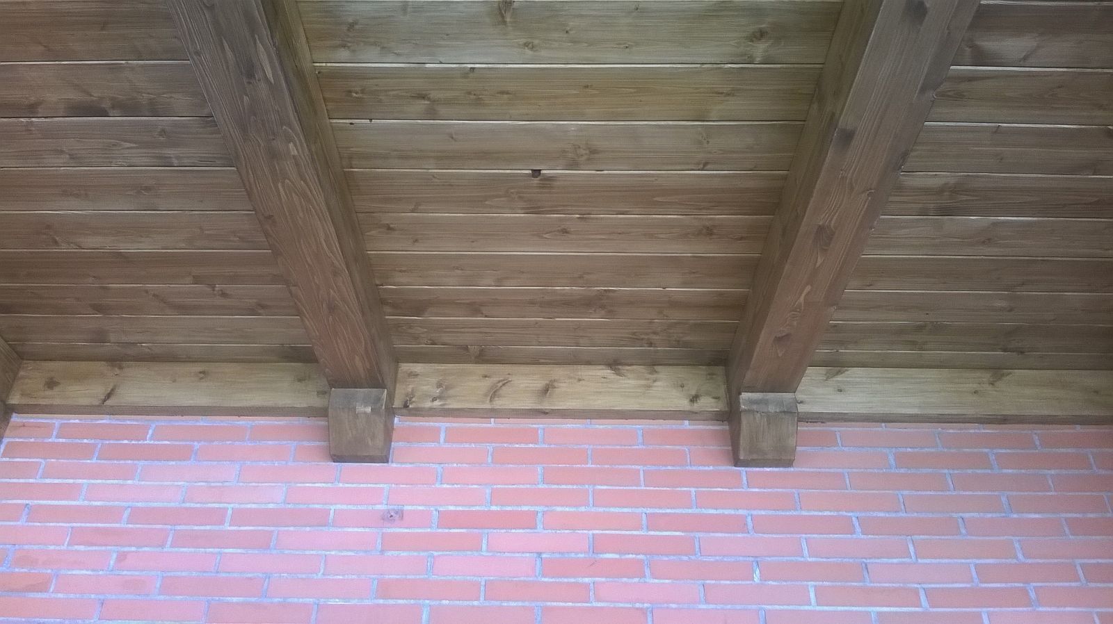 Una pared de ladrillos con un techo de madera encima.