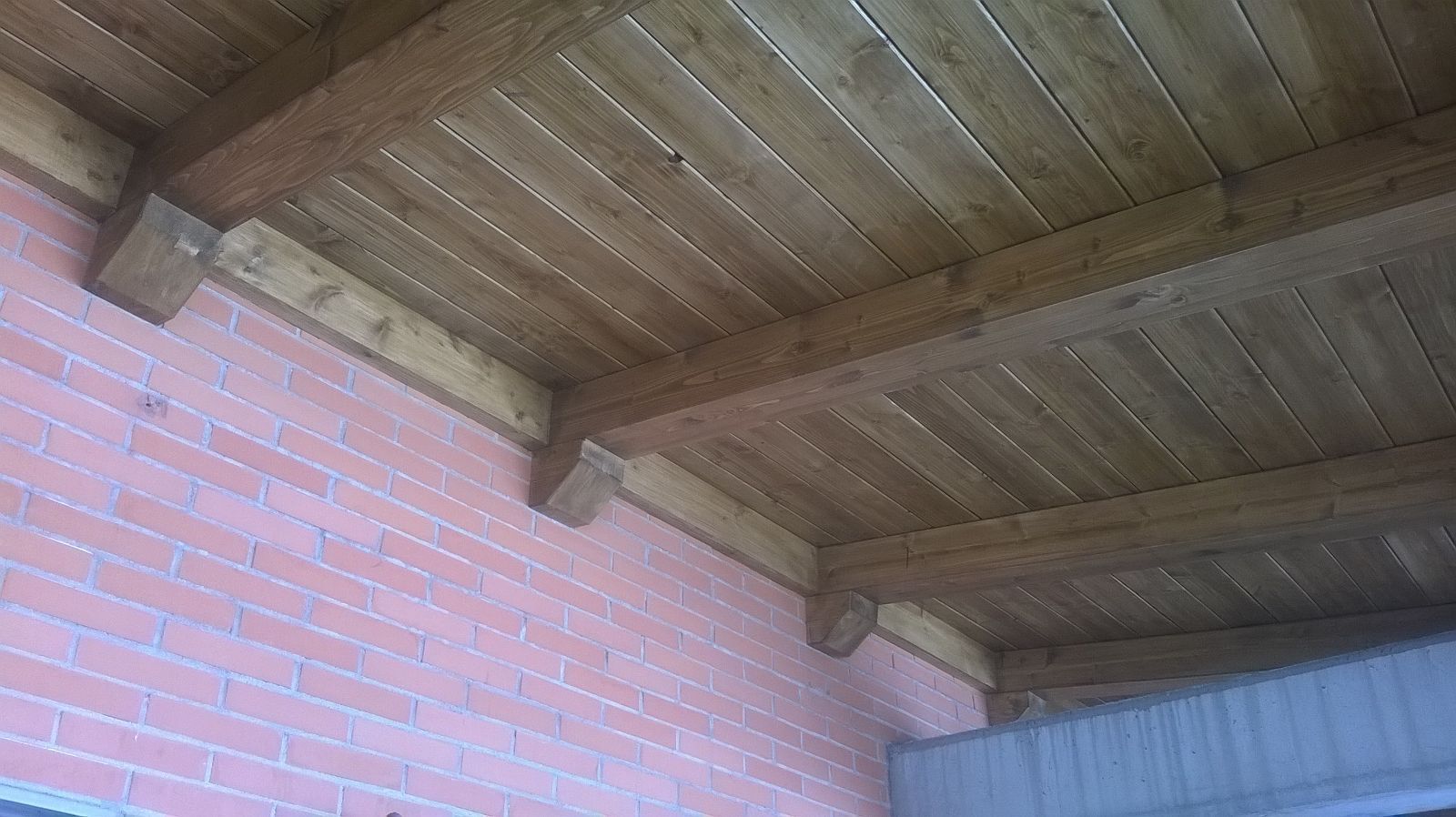 Un techo de madera con una pared de ladrillo al fondo.