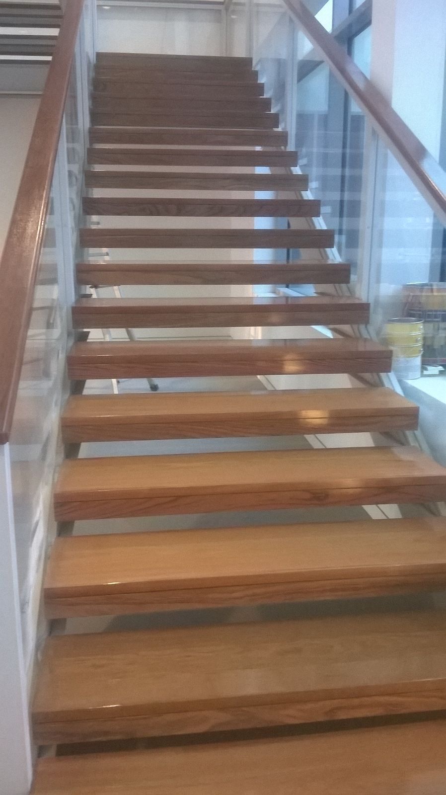 Una escalera de madera con barandilla de vidrio en un edificio.