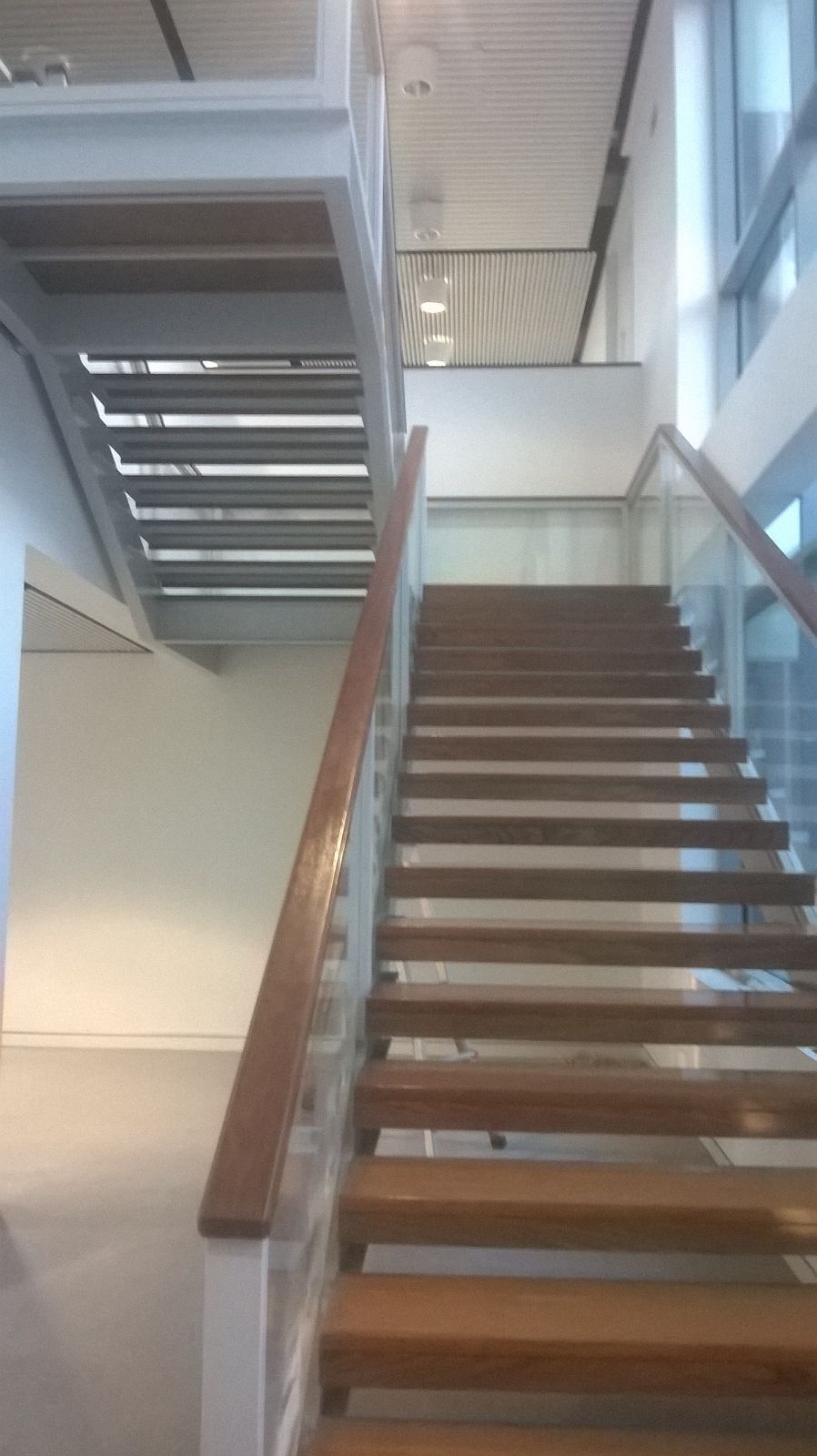 Una escalera de madera con barandilla de vidrio en un edificio.