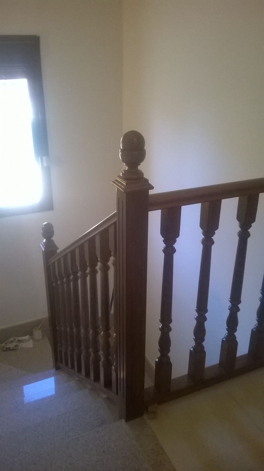 Una escalera con barandilla de madera y una ventana.