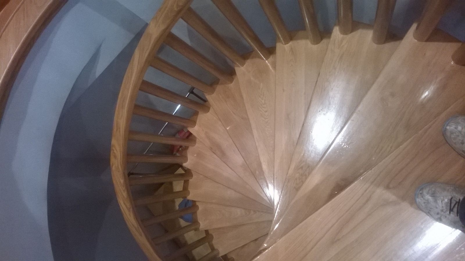 Una persona está parada en una escalera de caracol de madera.