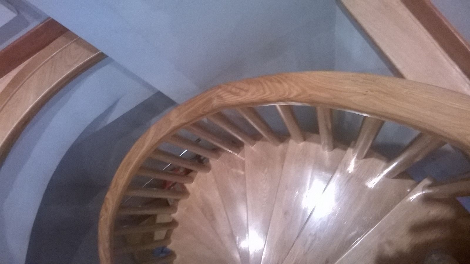 Un primer plano de una escalera de caracol de madera con barandilla de vidrio.