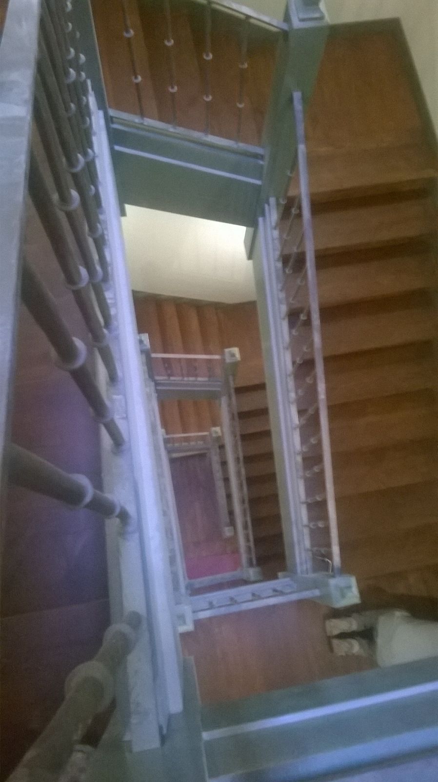 Una persona está mirando hacia abajo a una escalera de madera en una casa.