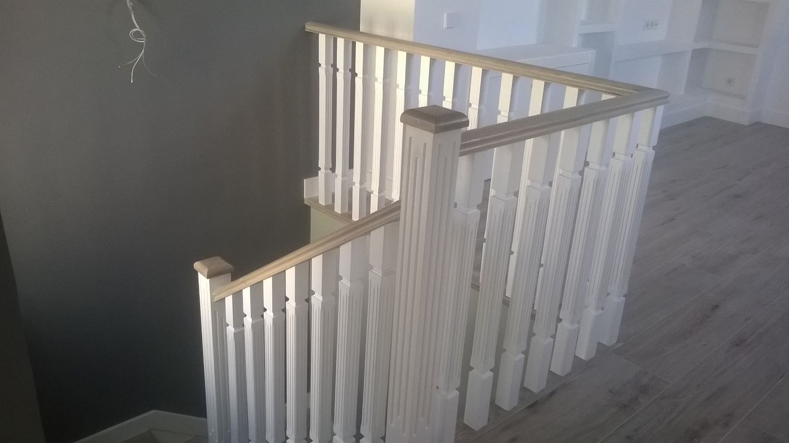 Una escalera de madera con barandillas blancas y suelo de madera.
