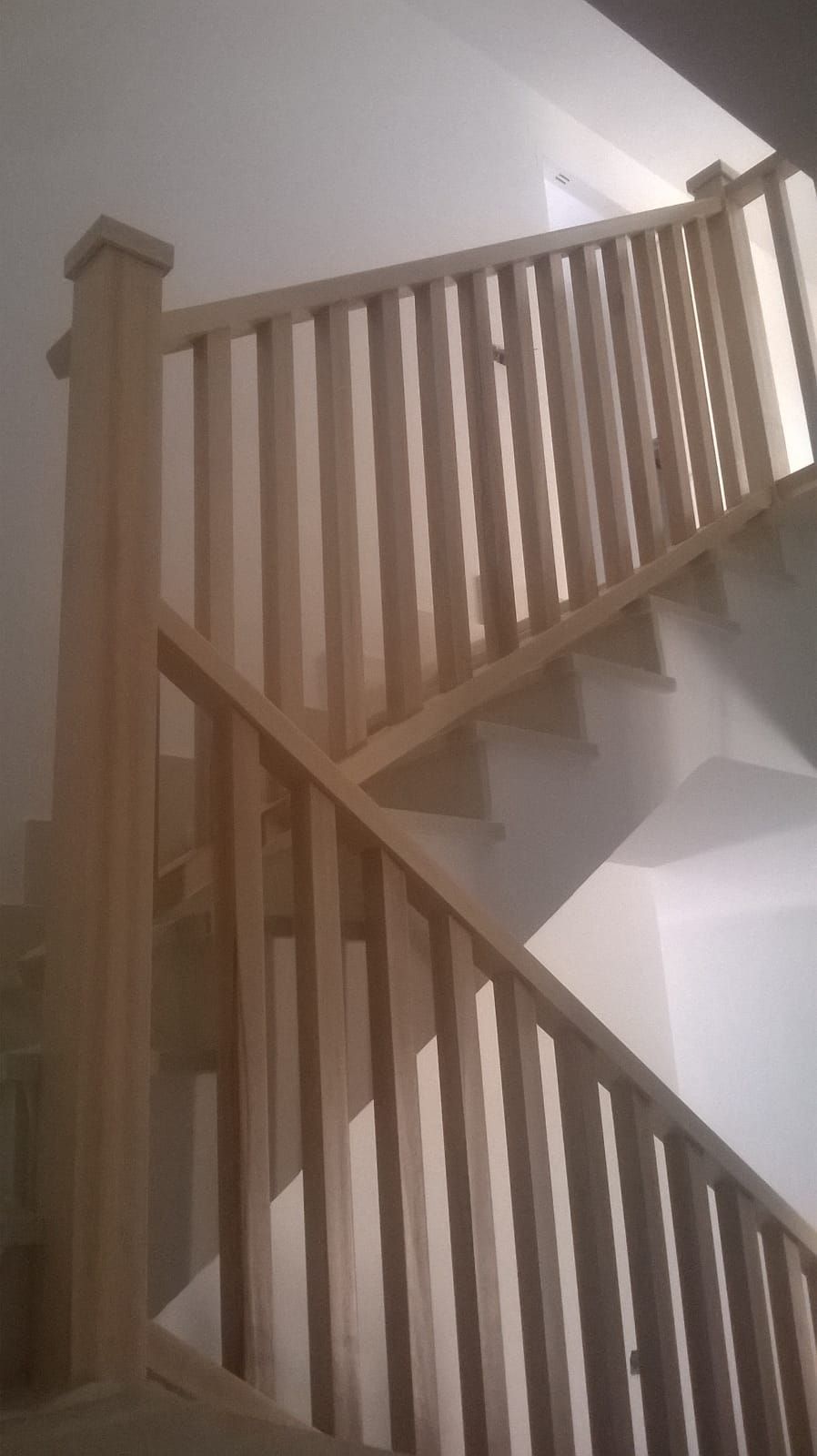 Una escalera con barandilla de madera que sube y baja.