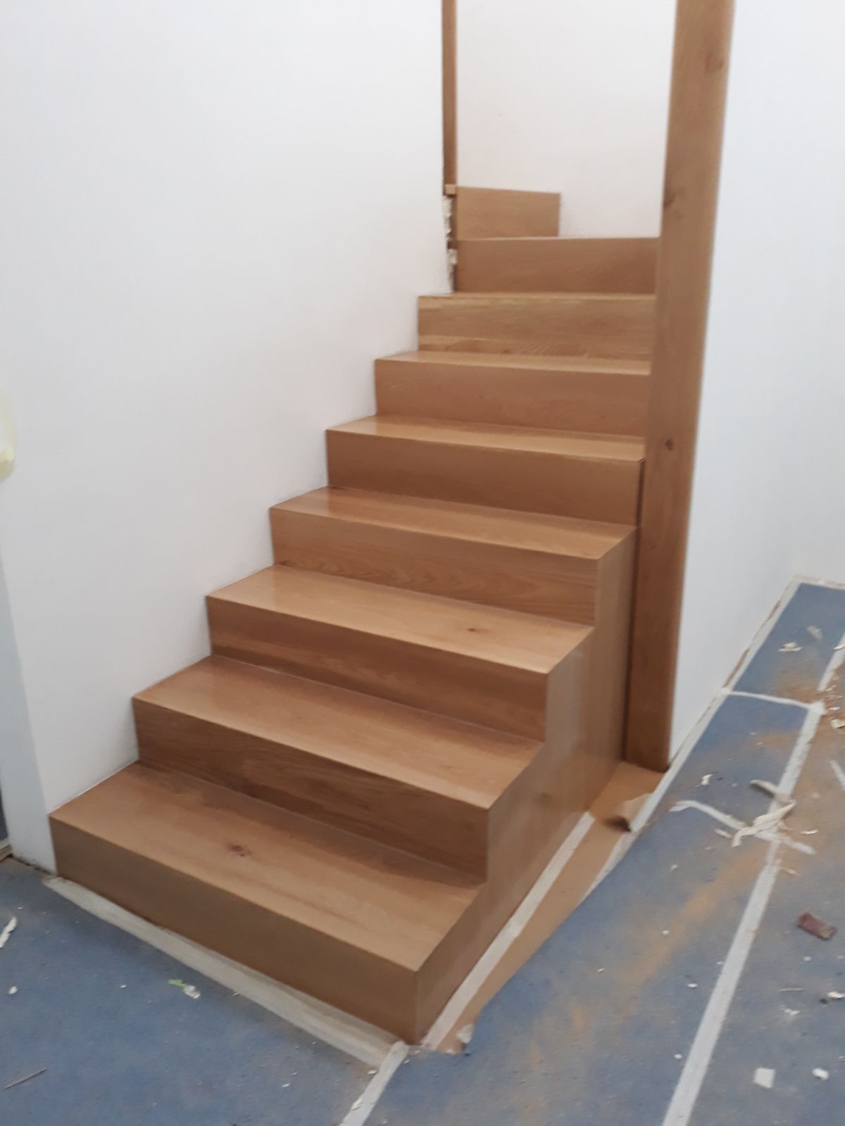 Una escalera de madera con una pared blanca detrás.