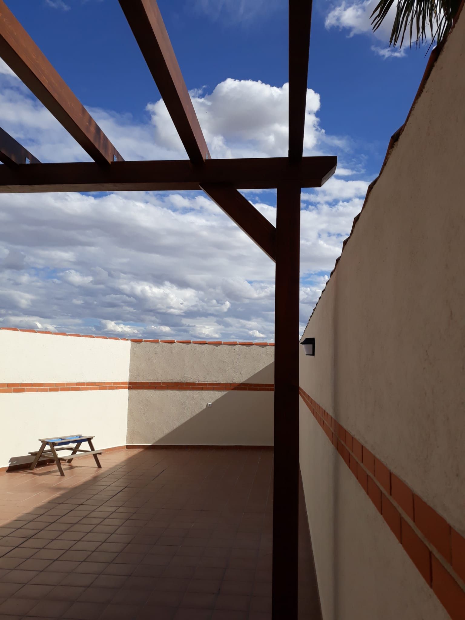 Un patio con pérgola y pared de ladrillo.