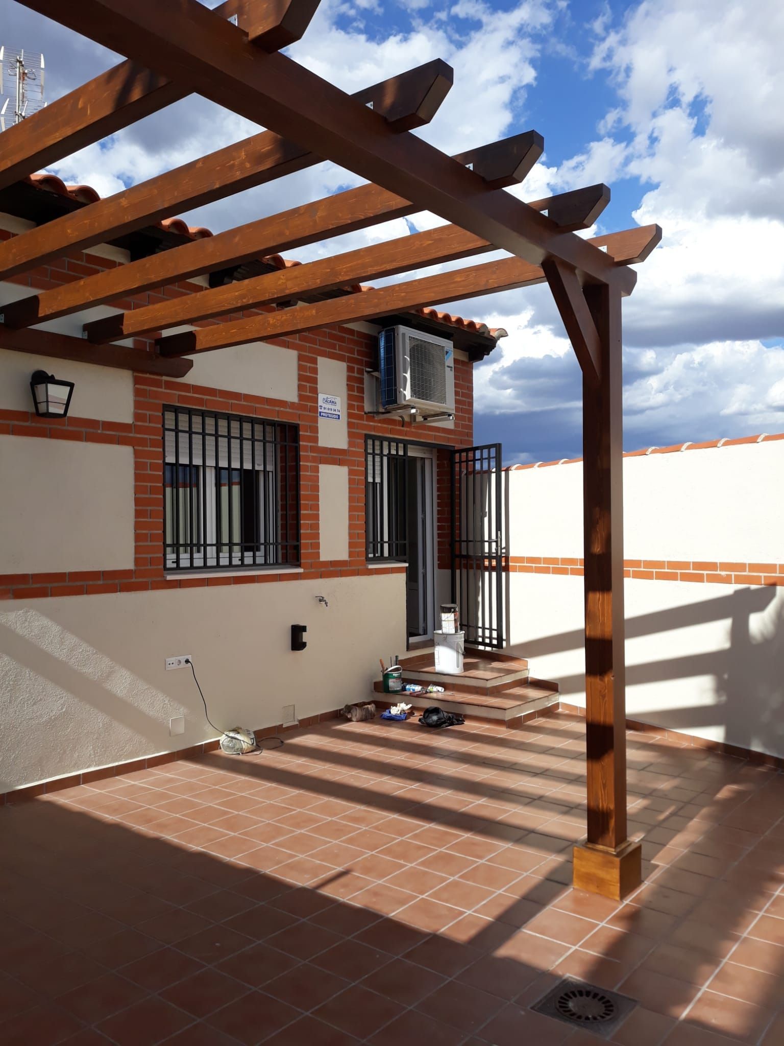 Un edificio de ladrillo con una pérgola de madera encima.