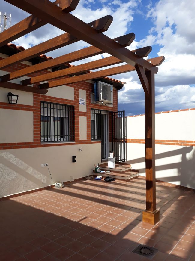 Un edificio de ladrillo con una pérgola de madera encima.