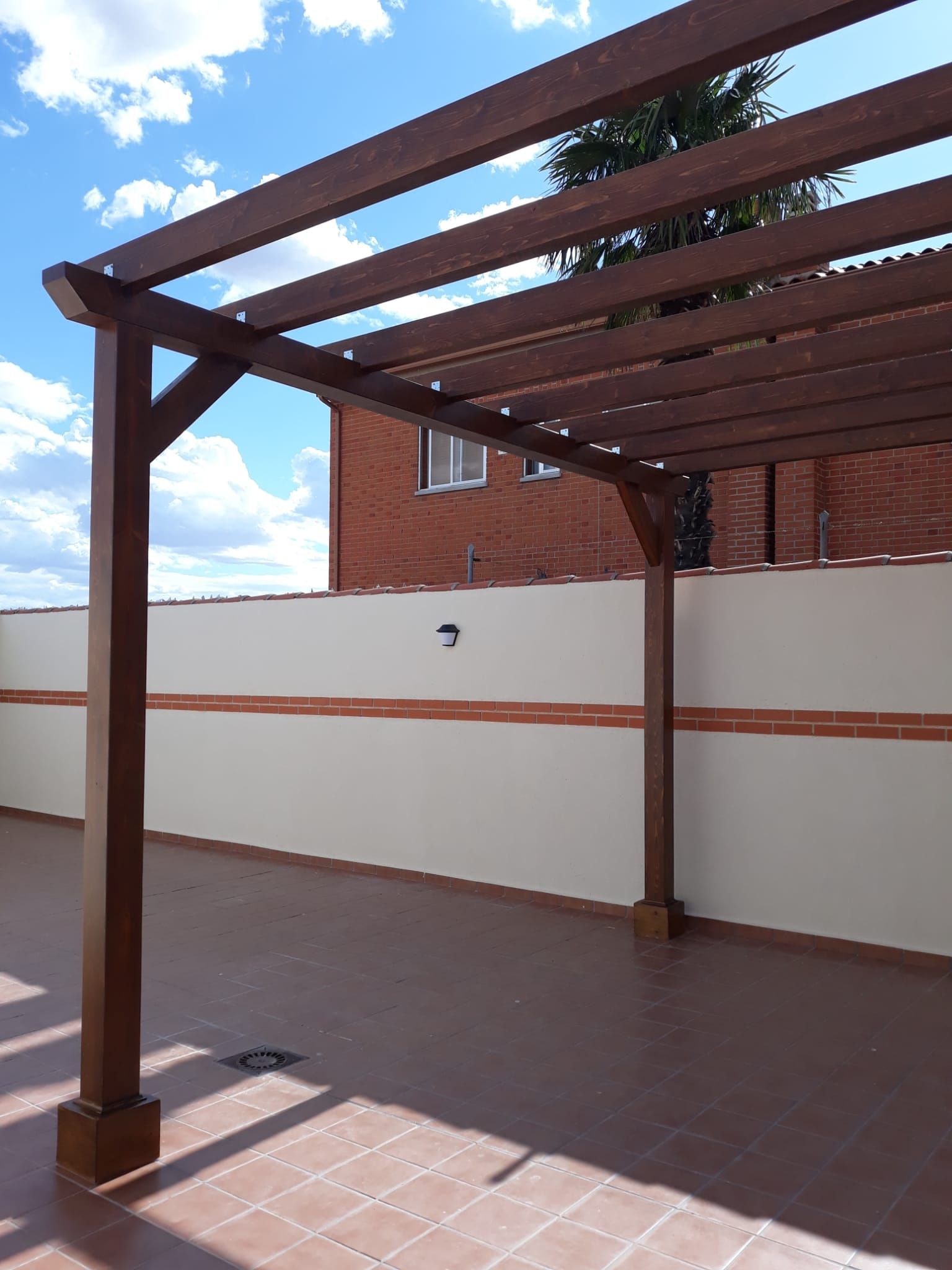 Un patio vacío con una pérgola de madera encima.