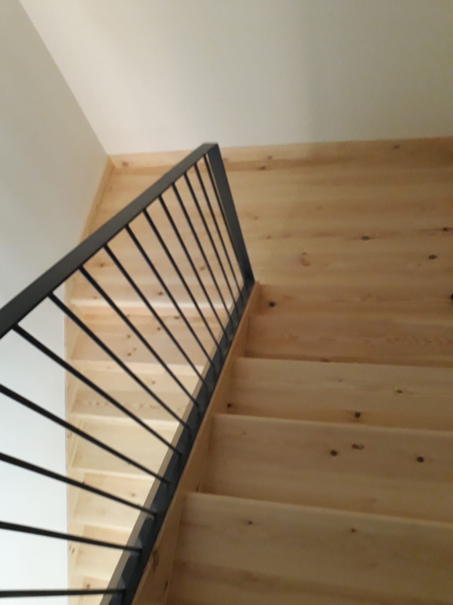Una escalera de madera con barandilla de metal negro.
