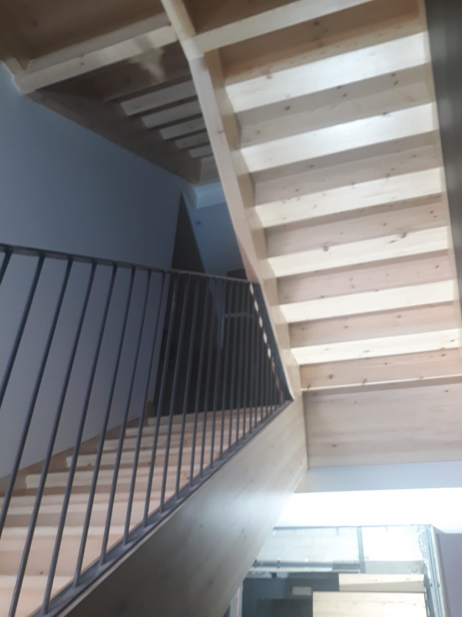 Una escalera de madera con barandilla de metal en un edificio.