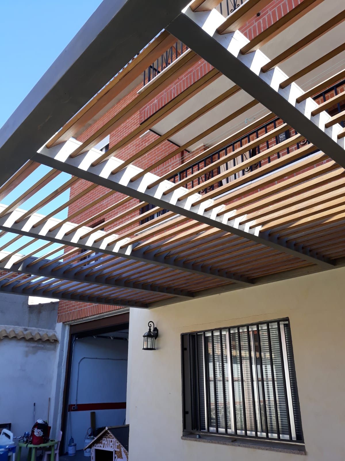 Una casa con una pérgola encima y una ventana.
