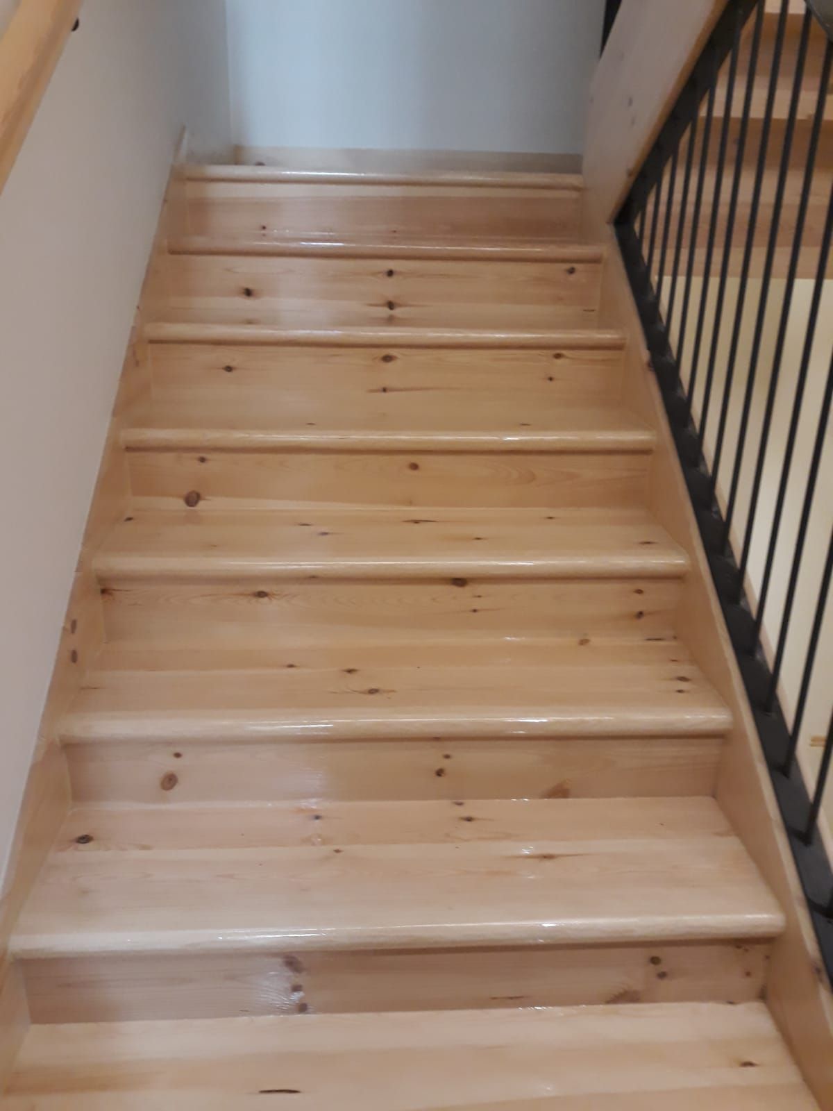 Un primer plano de una escalera de madera con barandilla de metal.