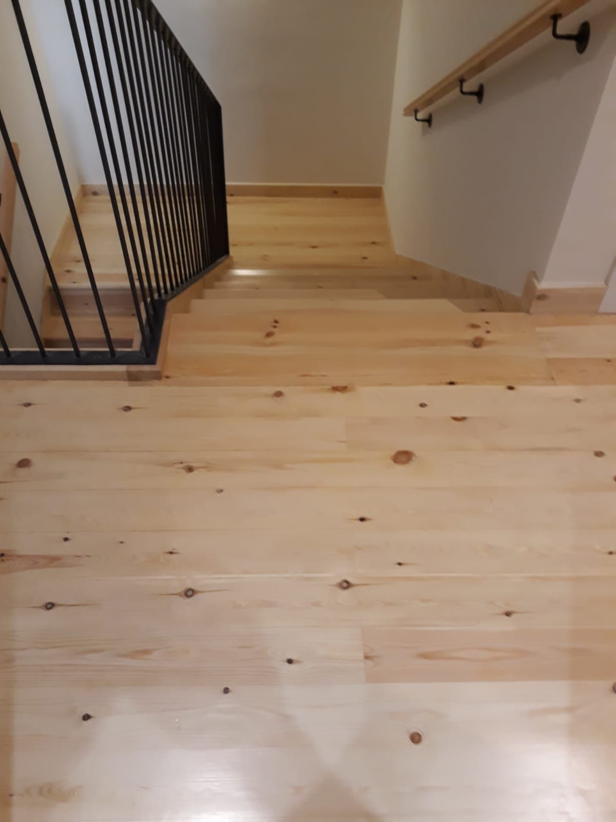 Una escalera de madera con barandilla de metal y suelo de madera.