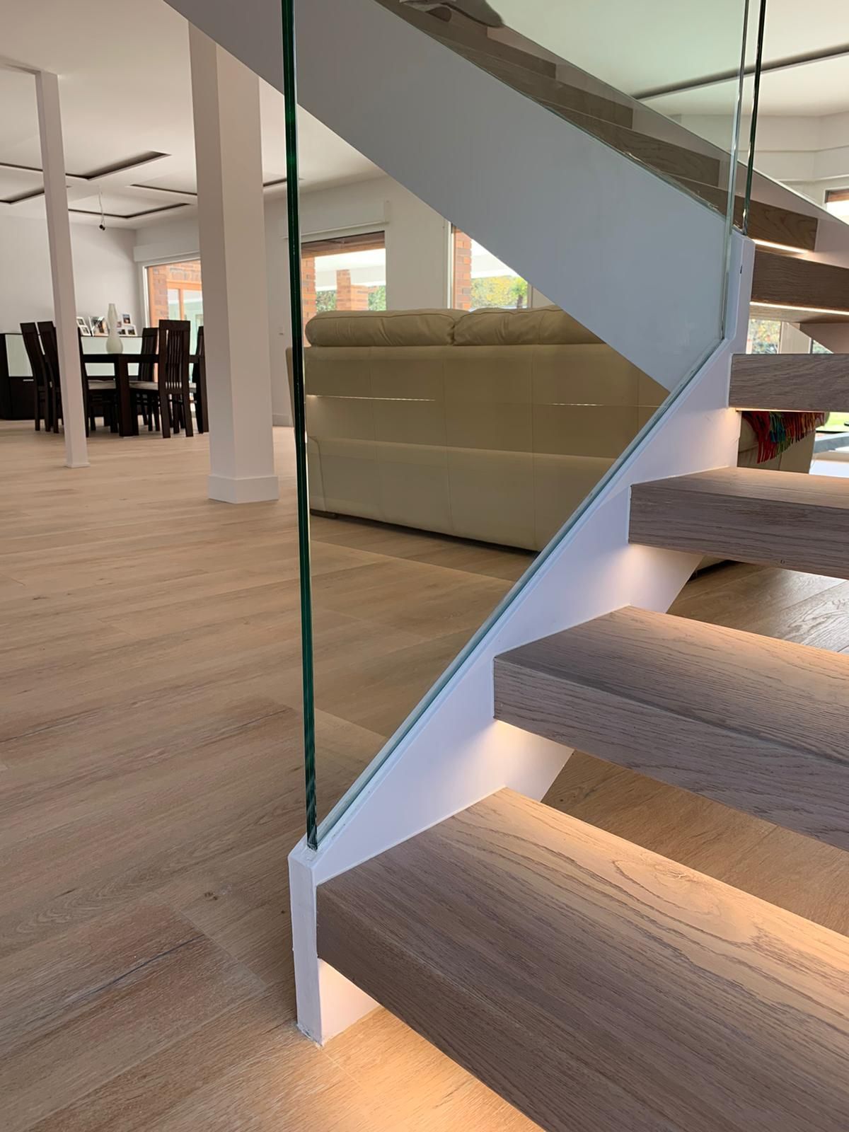 Una escalera con barandilla de cristal en una sala de estar.