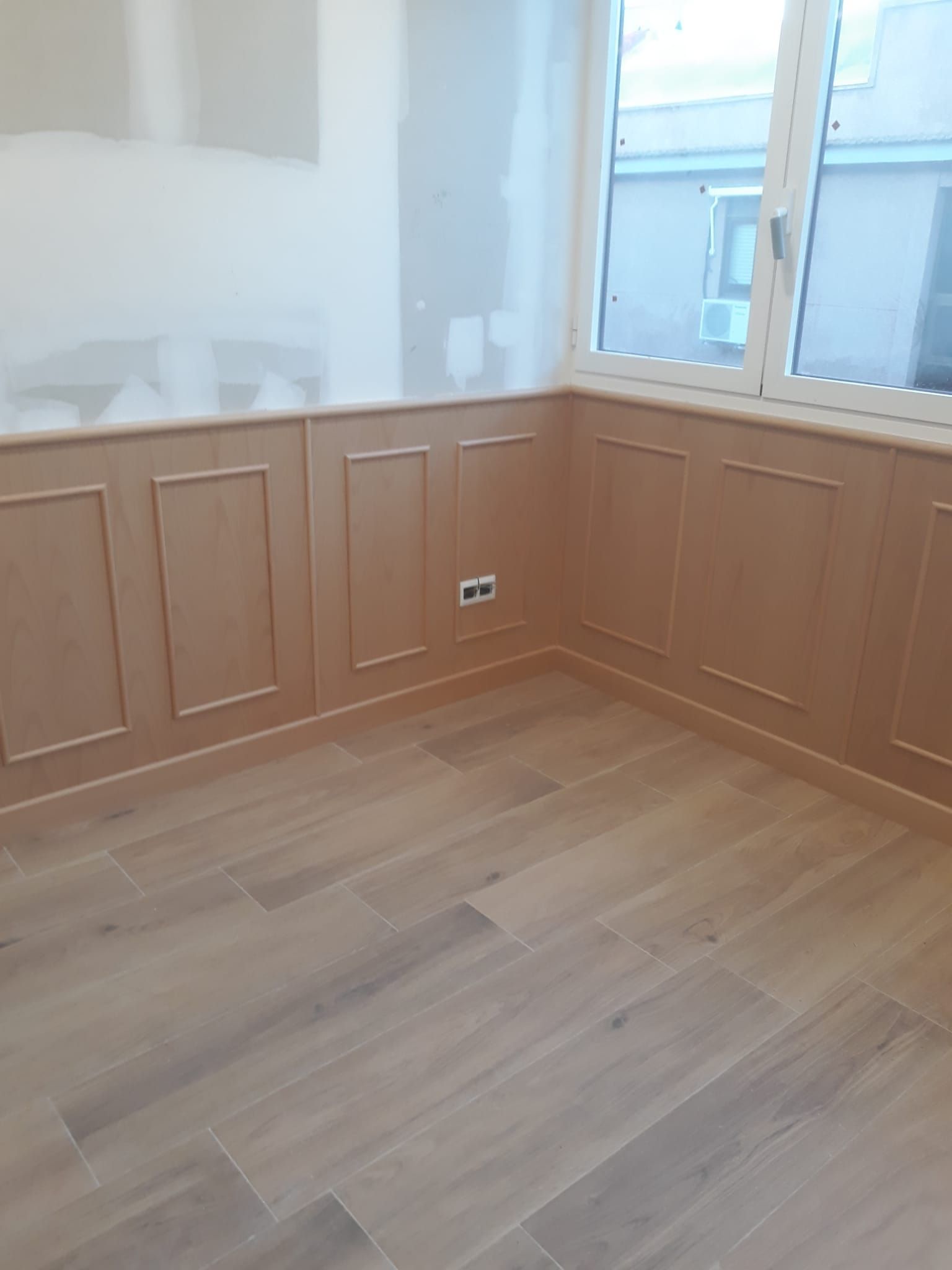 Una habitación vacía con paneles de madera y una ventana.