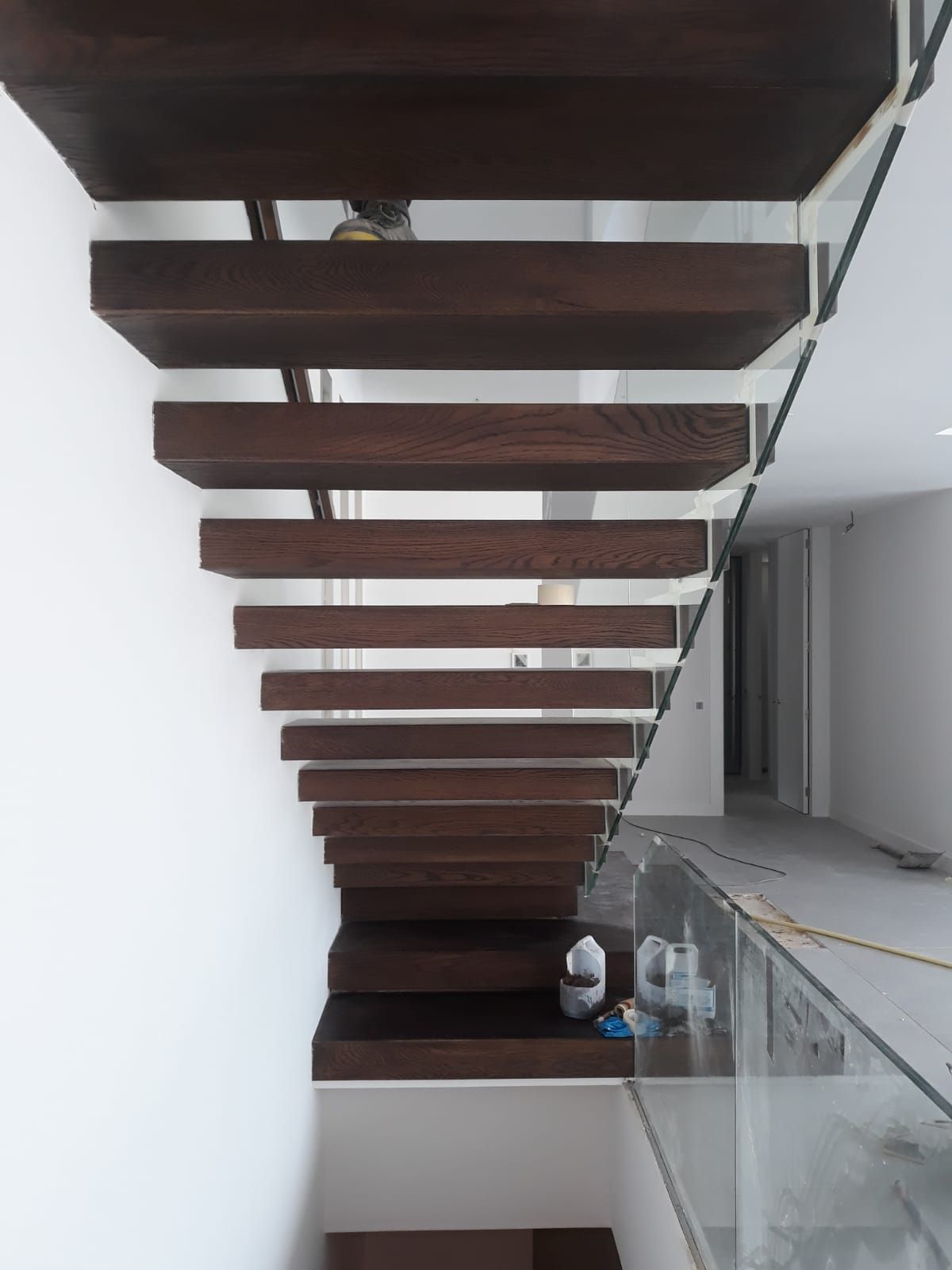 Una escalera de madera con barandilla de vidrio en una casa.