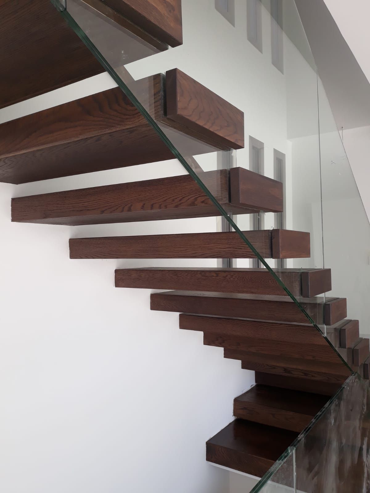 Una escalera con escalones de madera y barandilla de cristal.