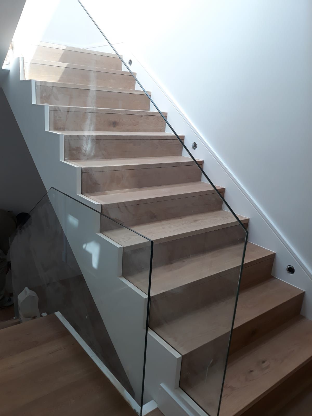 Una escalera con escalones de madera y barandilla de cristal.
