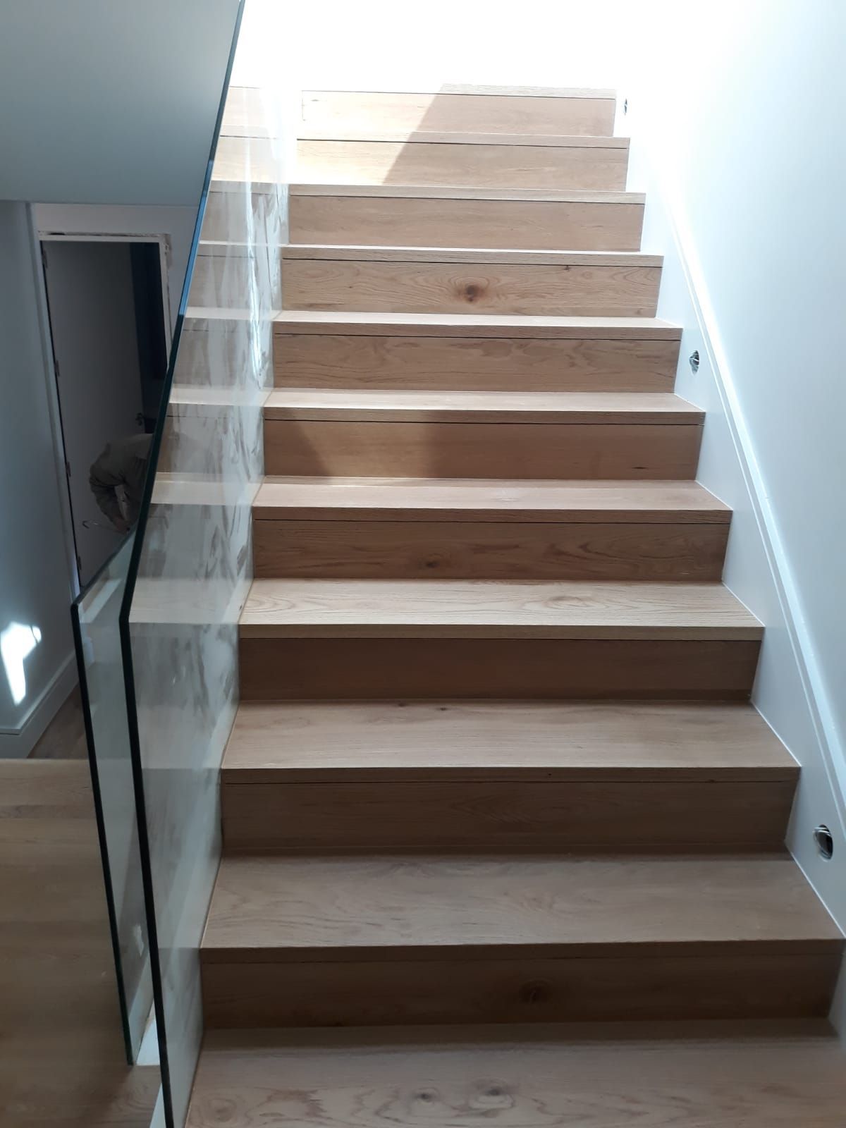 Una escalera de madera con barandilla de cristal en una casa.