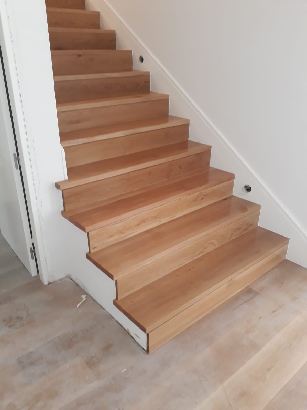 Un conjunto de escaleras de madera con barandilla blanca.