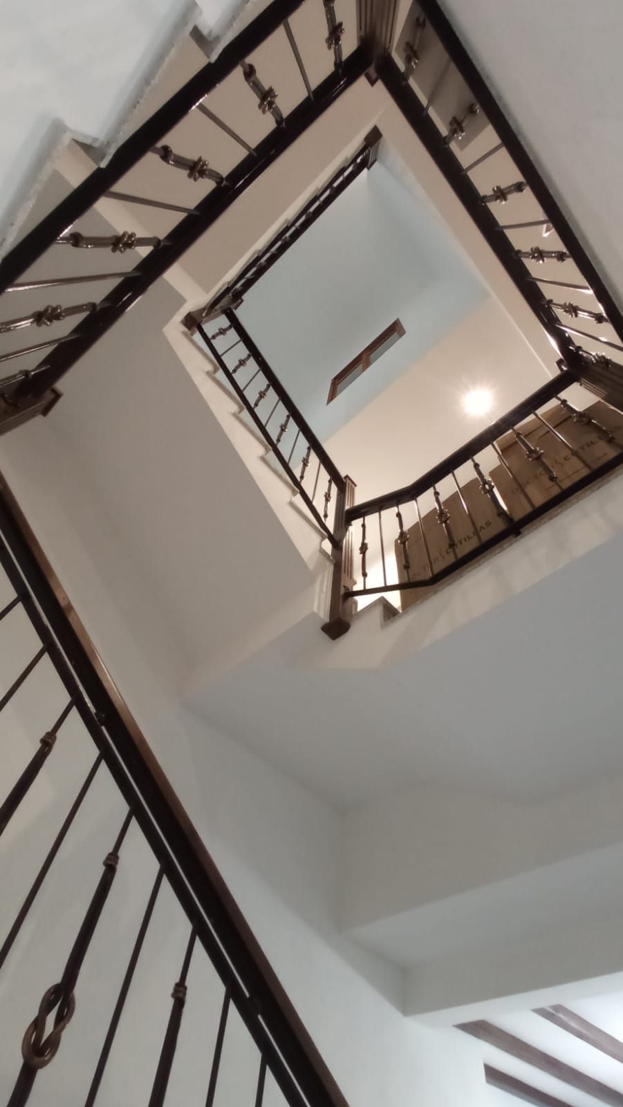 Mirando hacia arriba a una escalera con barandilla de hierro forjado