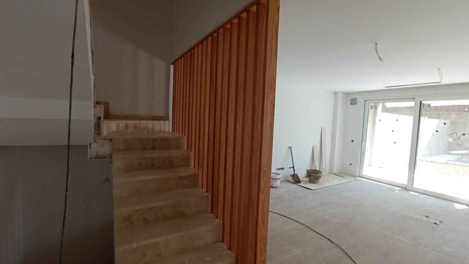 Una escalera con barandilla de madera en una habitación con una puerta corrediza de vidrio.