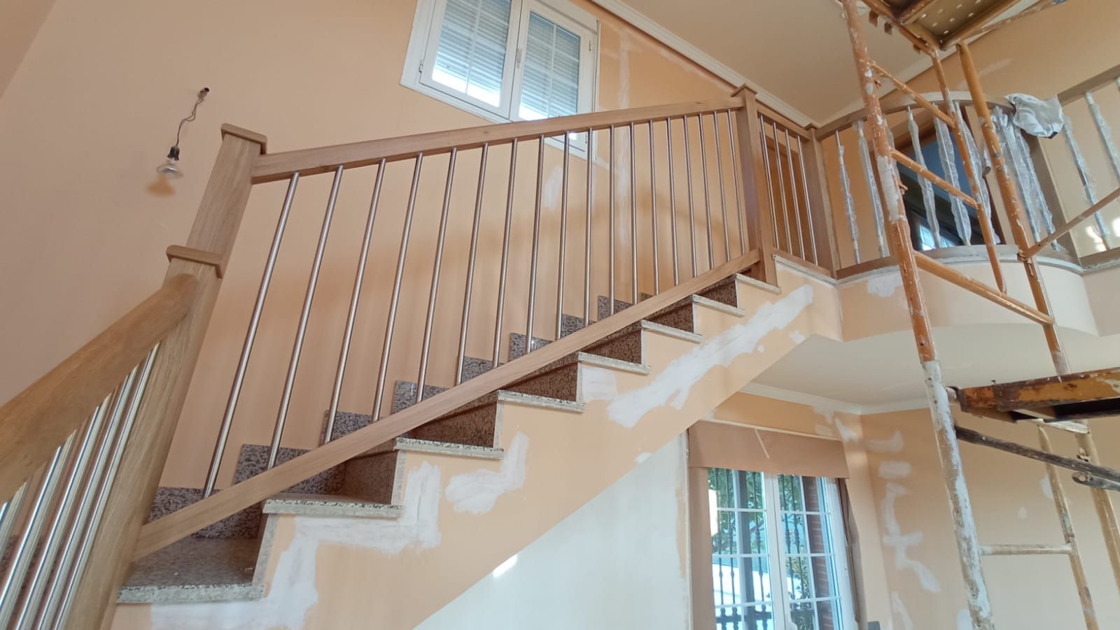 Una escalera de madera con barandilla de metal en una casa en construcción.