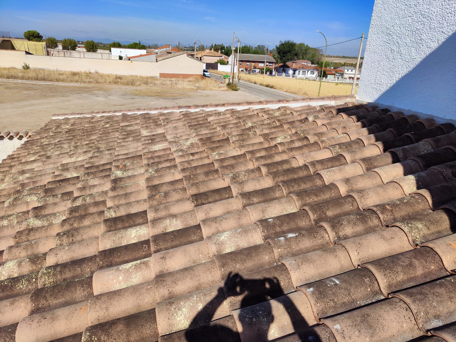 Una persona está tomando una fotografía de su sombra en un techo de tejas.