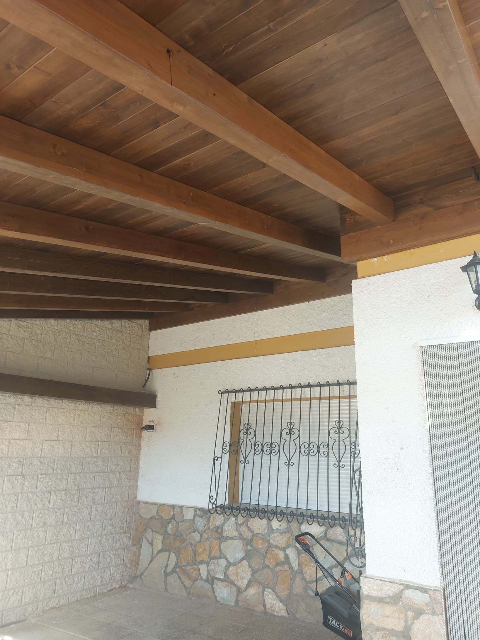 Una habitación con techo de madera y pared de piedra.