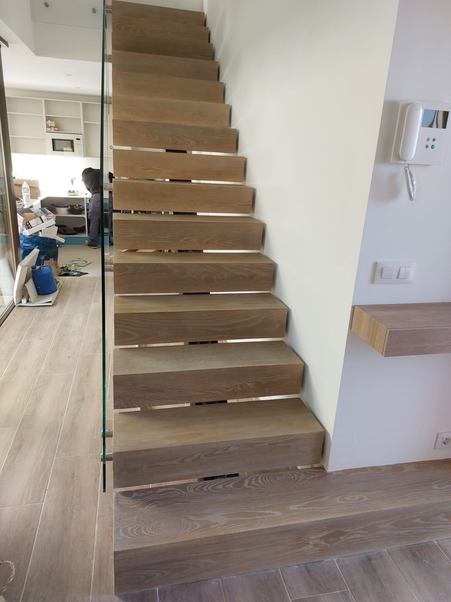 Una escalera de madera con barandilla de vidrio en una habitación.