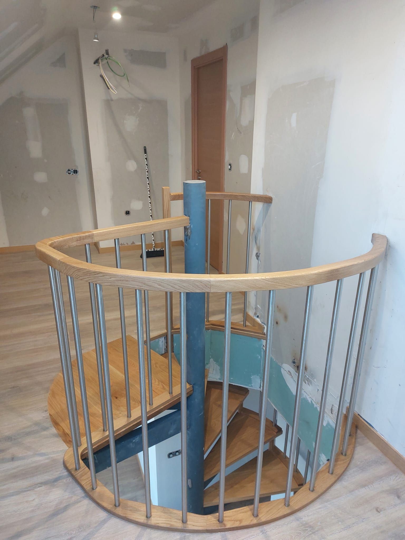 Una escalera de caracol de madera con barandilla de metal en una habitación.